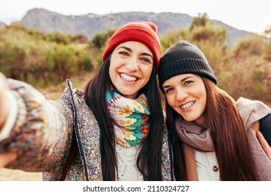 Two Young Beautiful Hiker Women Taking Selfie Portrait On The Top Of Mountain - Happy Smiling Sisters Enjoying Together - Hiking And Climbing Cliff