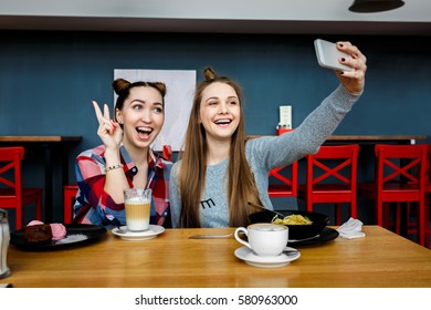 two young beautiful hipster women sitting at cafe, stylish trendy outfit, europe vacation, street style, happy, having fun, smiling, sunglasses, looking at smartphone, taking selfie photo, flirty - Shutterstock ID 580963000