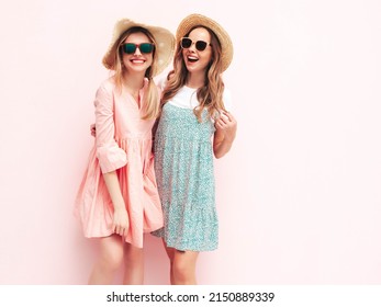 Two Young Beautiful Smiling Brunette Hipster Female In Trendy Summer Dresses. Sexy Carefree Women Posing Near Pink Wall. Positive Models Having Fun. Cheerful And Happy. In Hats 