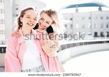 Two young beautiful smiling hipster female in trendy summer clothes. Carefree women posing in the street. Positive models having fun outdoors at sunny day. Cheerful and happy