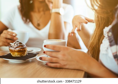 Two young and beautiful women meet at the bar for a cappuccino and to chat. A woman speaks gesturing while the other is listening - Powered by Shutterstock