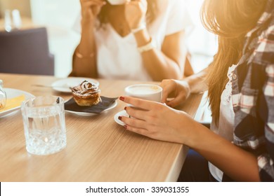 Two young and beautiful women meet at the bar for a cappuccino and to chat. A woman speaks while the other is drinking - Shutterstock ID 339031355