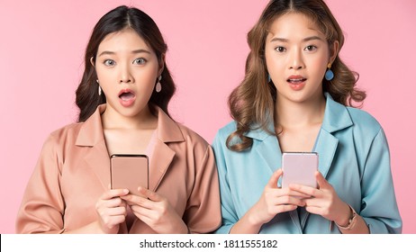 Two young beautiful women showing shocked expression portrait isolated on pink background