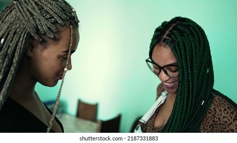 Two young black latina women showing their braided hair. Hispanic girls with cool box braids green hairstyle