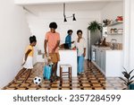 Two young black siblings, a brother and a sister, play with a soccer ball in their kitchen at home. Happy Brazilian kids having fun during a relaxed family afternoon, with their parents standing by.