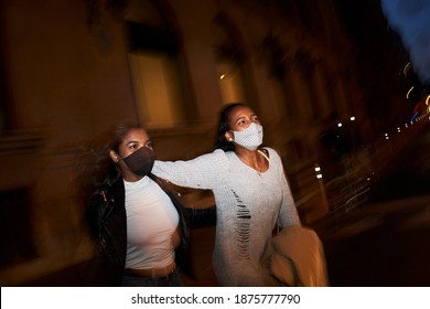 Two Young Black Women Friends Walking At Night In The City With Facial Mask.