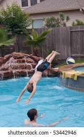 Two Young Boys Enjoying A Swim In The Backyard Swimming Pool.