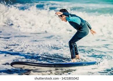 Two young boys having a beginner surf lesson and having fun in a sunny day in summer