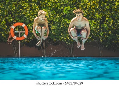 Two young boys having fun diving into the swimming pool.View from the water of happy teenagers jumping in. Tourist people enjoying summer holiday together. Youth, summer vacation, happiness concept - Powered by Shutterstock