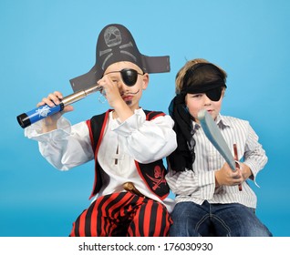 Two Young Boys In Pirate Costumes Holding Telescope And Sword.