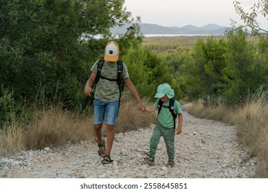 Two young boys walking on rocky forest path with backpacks, exploring nature together on sunny day. Concept of adventure, childhood, and family outdoor activities. High quality photo - Powered by Shutterstock