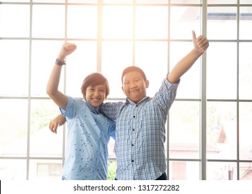 Two Young Boys Who Are Friends With Each Other Standing With Their Arms Around Each Other Smiling Indoor