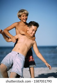 Two Young Boys Wrestling At The Beach