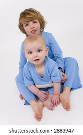 Two Young Brothers With Blue Eyes Dressed In Matching Pyjamas