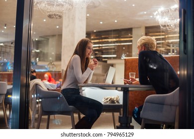 Two Young Business People, Freelancer Working On Same Project Meet For Discussion And Work At Coworking Hub Or Office Cafe At Night Time, Talk And Discuss Important Topics At Casual Atmosphere