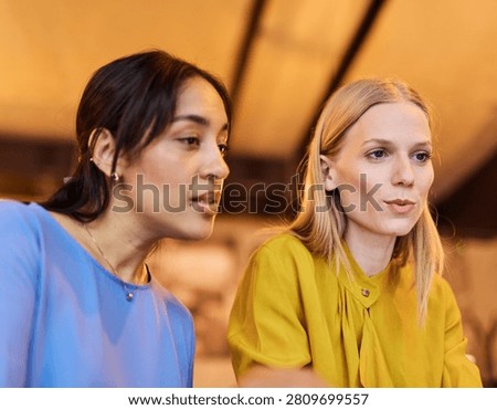 Two young business wmoen using laptop in caffee bar or office