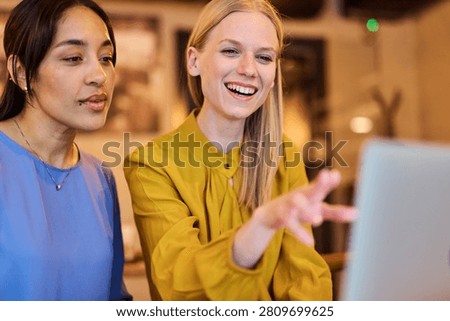 Two young business wmoen using laptop in caffee bar or office