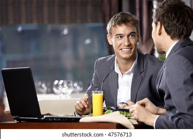 Two young businessmen have supper at restaurant