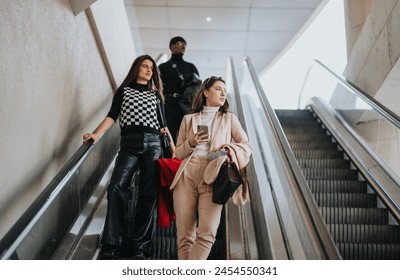 Two young businesspeople commute on an escalator inside a contemporary office building, one focused on her smart phone. - Powered by Shutterstock