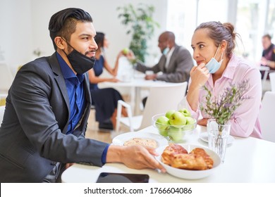 Two Young Businesspeople As A Couple Flirting In The Cafeteria With A Face Mask On Their Chin