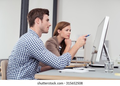 Two Young Businesspeople Sitting At The Table And Looking At The Figures On The Computer Screen