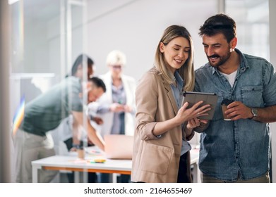 Two young businesspeople using a digital tablet while standing in a boardroom. Two business colleagues having a discussion during a meeting. - Shutterstock ID 2164655469