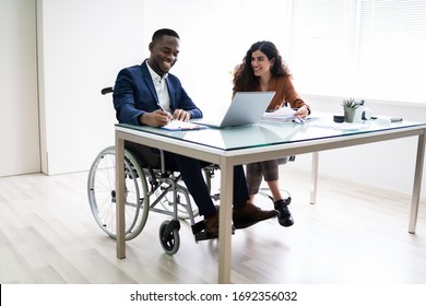 Two Young Businesspeople Working On Laptop At Workplace - Powered by Shutterstock