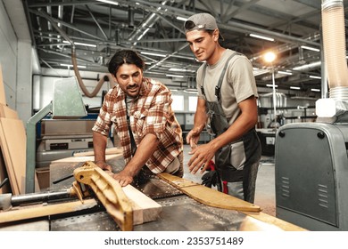 Two young carpenters working with wood standing at table in workshop - Powered by Shutterstock