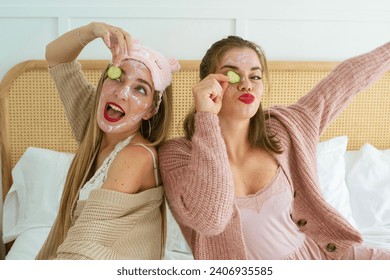 Two young caucasian girls in pajamas, sitting in their bed, embracing a girls' concept with a skin care routine, white masks, cucumber, and celebrating natural beauty in their morning routine. - Powered by Shutterstock