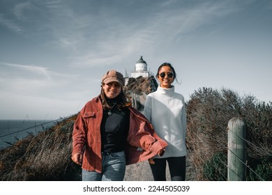 two young caucasian women walking smiling happily down the narrow dirt road coming from the lighthouse next to the wooden fence, nugget point, new zealand - Powered by Shutterstock