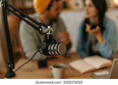 Two young cheerful people recording a podcast in a studio. Focus on the microphone. Podcast concept - Powered by Shutterstock