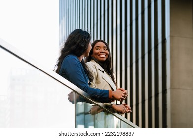 Two young cheery multinational women talking while standing outdoors at the city street - Shutterstock ID 2232198837