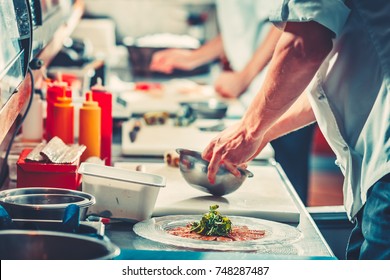 Two Young Chefs In White Uniform Preparing Delicious Fish Meat Snack Salad, Only Hands Close Up. Interior Of Modern Restaurant Kitchen. Food Concept. Vintage Instagram Color Filter Toning