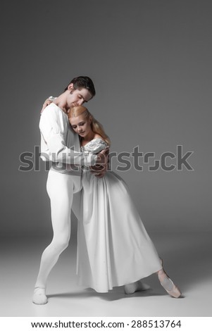 Two young classic ballet dancers practicing. attractive dancing performers  in white suits over gray background