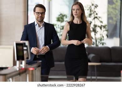 Two young colleagues in formal wear hold access cards, approaching entrance to office, male female business people leaving workplace for lunch, talking, having friendly conversation ending working day - Powered by Shutterstock