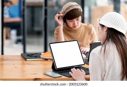Two young college student using computer for online learning together in classroom, blank screen for graphic design.
