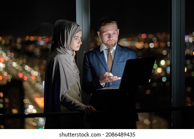 Two young confident colleagues preparing presentation at night meeting against traffic lights - Powered by Shutterstock