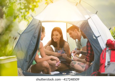 
Two young couple having fun on camping trip, sitting in tent talking and playing cards - Powered by Shutterstock
