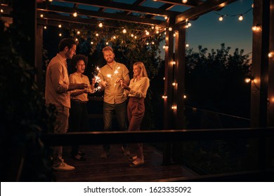 Two Young Couples Having Fun With Sparklers Together Outside At Night