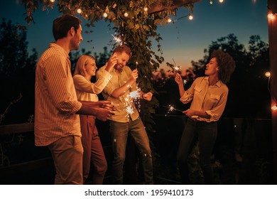 Two Young Couples Having Fun With Sparklers Together Outside At Night