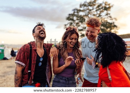 Two young couples are together at a summer music festival, having fun during the day party.