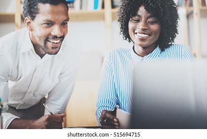 Two Young Coworkers Working Together In A Modern Coworking Studio.African Black Business Partners Using Laptop And Discussing New Startup Project.Horizontal,blurred