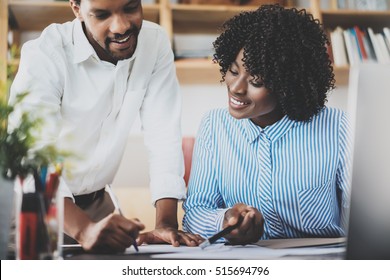 Two young coworkers working together in a modern office.Black business people discussing new startup project.Horizontal,blurred