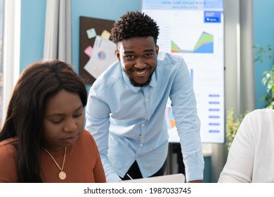 Two Young Dark-skinned Experienced Employees Spend The Morning In The Company During A Business Meeting, The Manager Supervises The Work Of His Colleagues, Smiles At The Camera