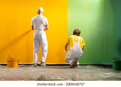 Two young decorators paint the wall yellow and green 