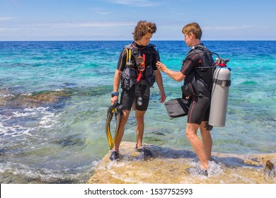 Two young divers checking their diving equipment in sea of Bonaire