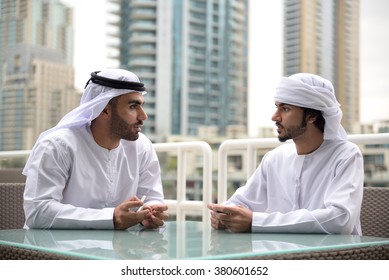 Two young Emirati arab friends talking in a restaurant