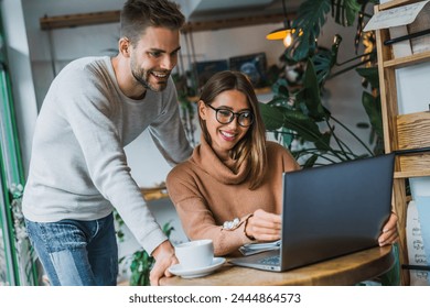 Two young entrepreneurs businesspeople discussion new project startup while sitting in coffee shop. Man and woman working remotely using laptop. Male female freelancers working together. Digital nomad - Powered by Shutterstock