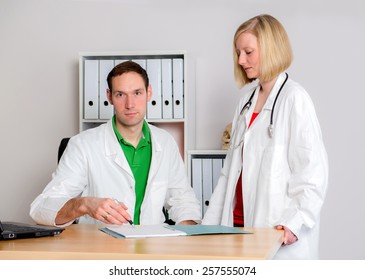 Two Young  Family Doctor In Her Office Woking Together