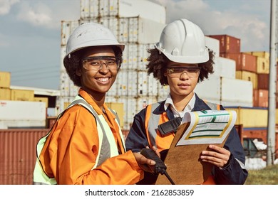 Two Young Female African Ladies Are Locating Shipping Containers Using A Radio In A Storage Yard In Johannesburg South Africa. They Are Wearing Protective Wear And Reflective Vests